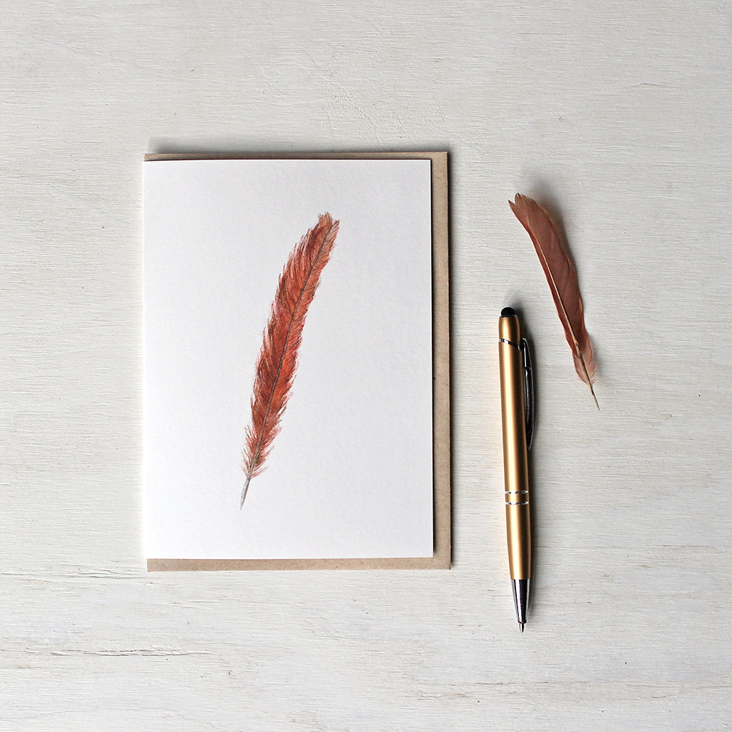 Note card featuring a watercolor painting of a female Northern cardinal's red orange tail feather. Artist Kathleen Maunder.