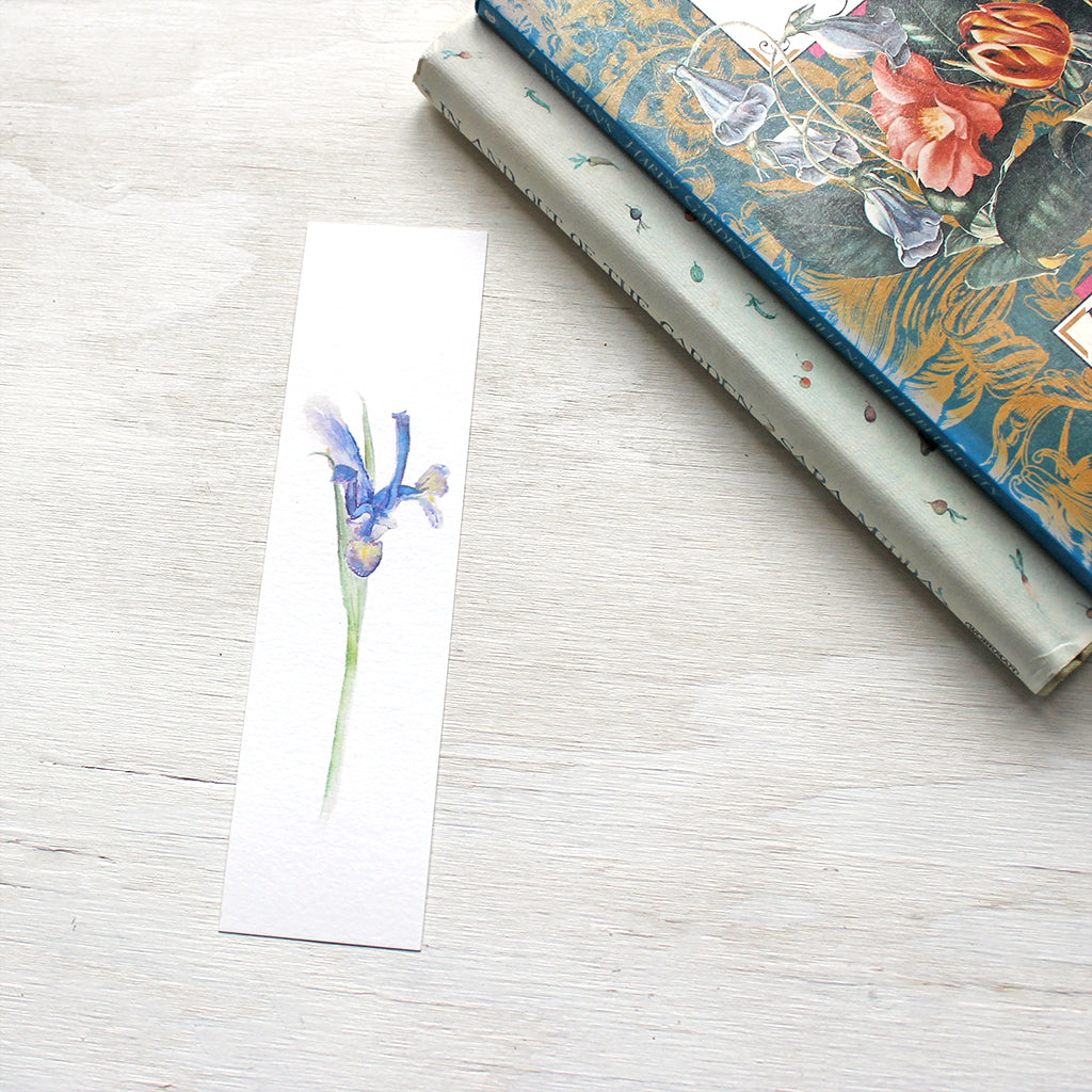A paper bookmark with a watercolor painting of a Siberian iris. Artist Kathleen Maunder.