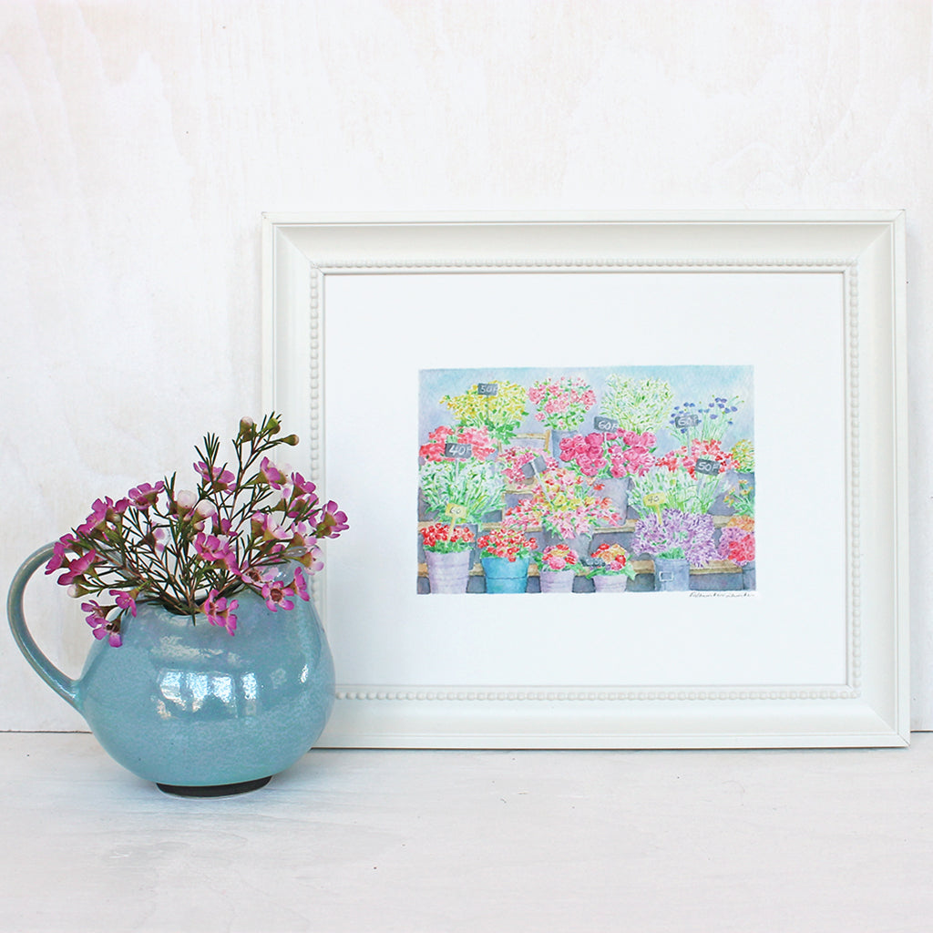 A reproduction of a beautiful watercolor painting of a flower stand at the Marché aux fleurs in Paris. Artist Kathleen Maunder.