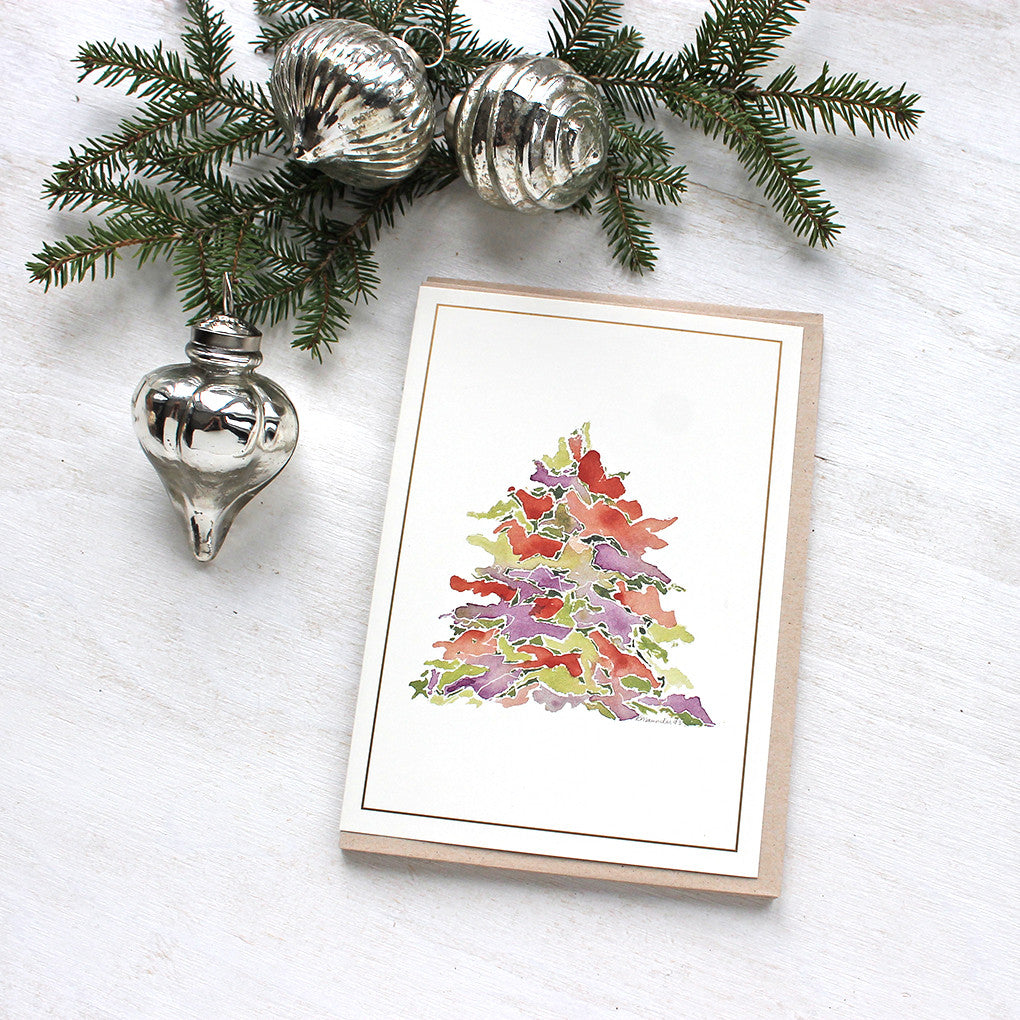 A holiday card featuring a multi-coloured Christmas tree painted in watercolor. Festive tones of red, green and purple. Artist Kathleen Maunder