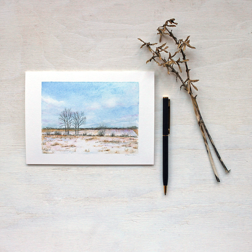 Note card featuring a watercolor painting of a snowy field and soft fluffy clouds. Artist Kathleen Maunder.