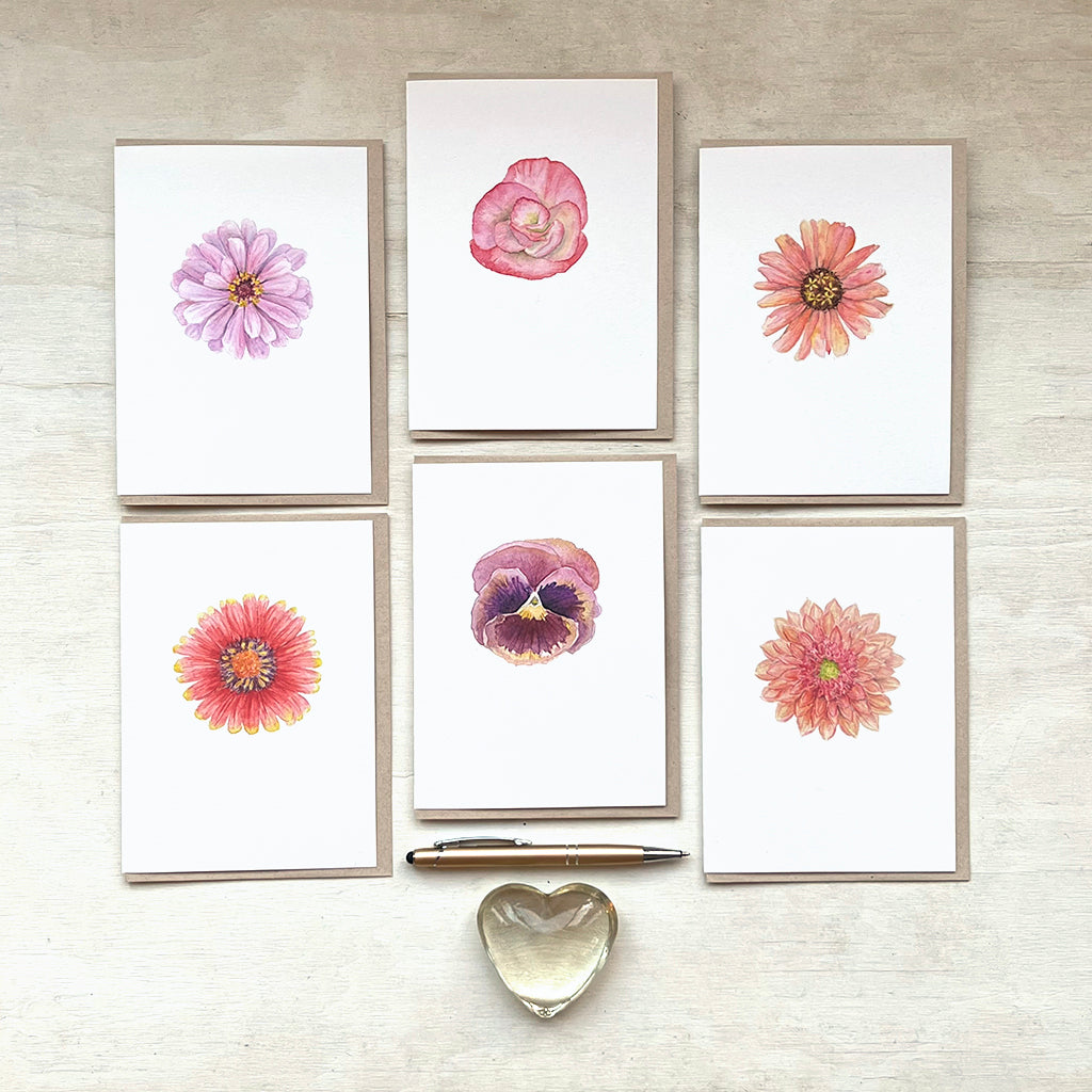 Set of six floral cards featuring botanical watercolour paintings by Canadian artist Kathleen Maunder. The photo also contains a gold pen and glass heart.
