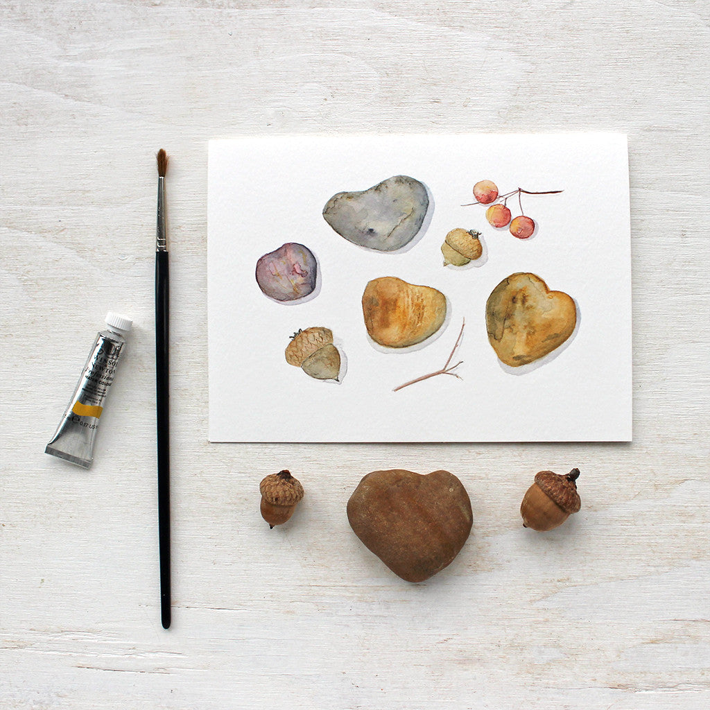 A lovely set of five note cards featuring a watercolor painting of heart-shaped stones, acorns and cranberries to create an autumn nature collection. Artist Kathleen Maunder