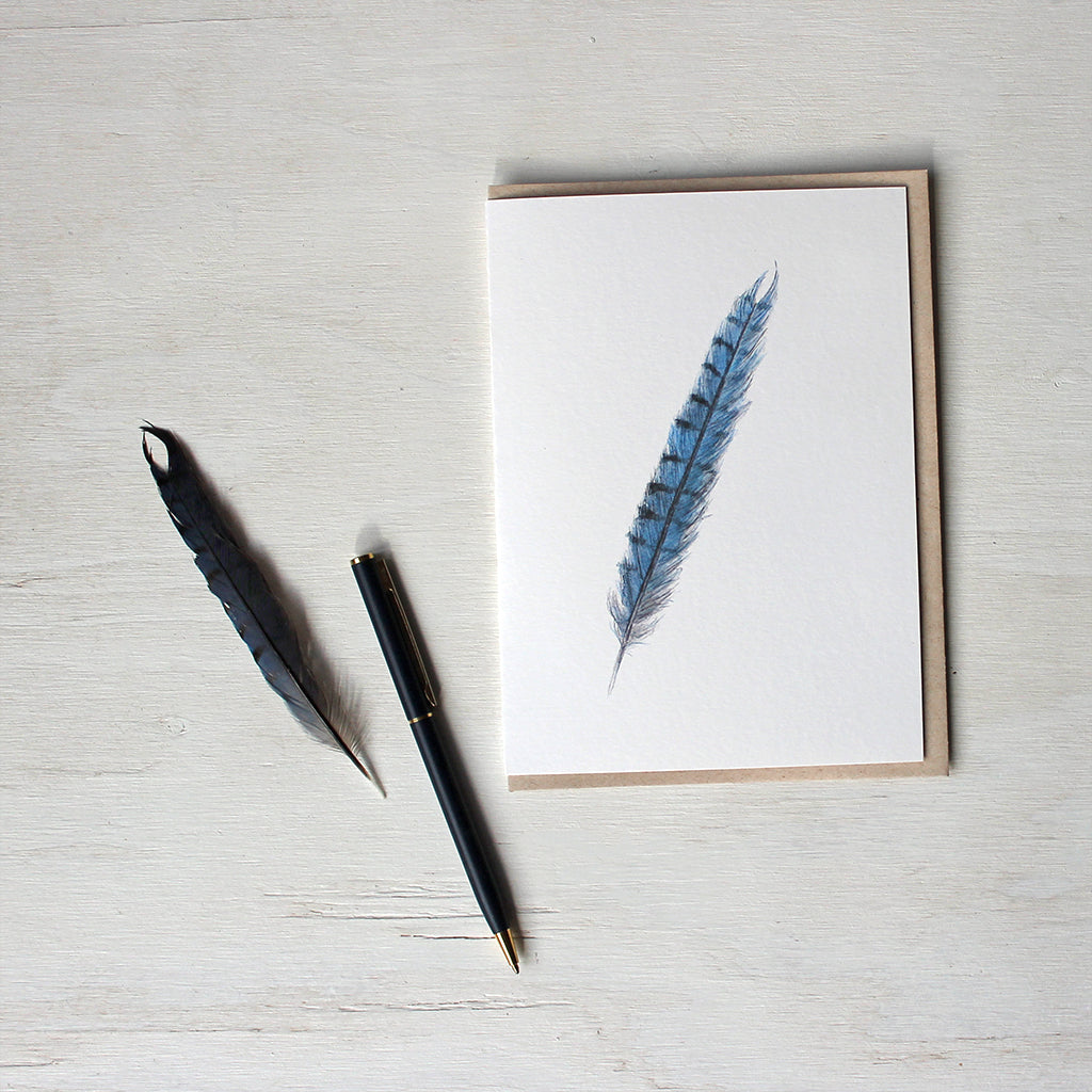 Note card featuring a watercolor painting of a blue jay feather. Artist Kathleen Maunder.  