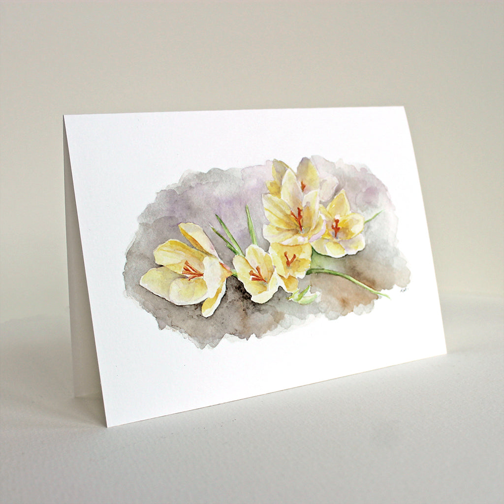 A note card featuring a watercolor painting of lovely pale yellow spring crocuses. Artist Kathleen Maunder.