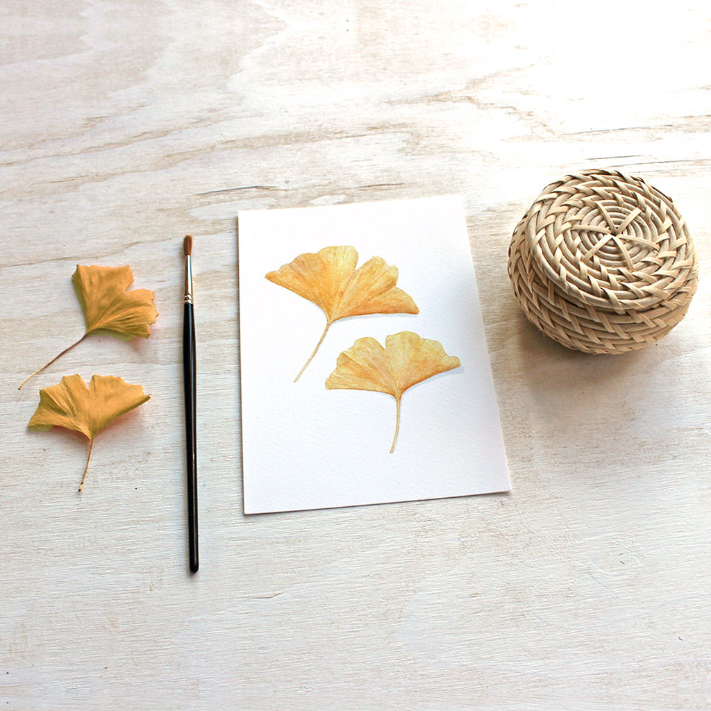 Lovely reproduction of an autumn watercolor painting of two yellow ginkgo leaves. Artist Kathleen Maunder