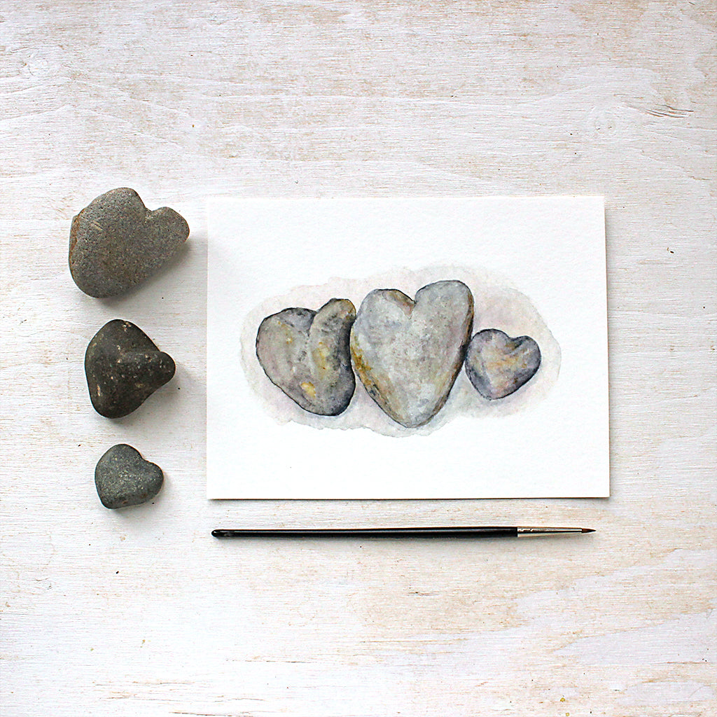 Watercolor painting of three beautiful heart-shaped beach rocks. Artist Kathleen Maunder