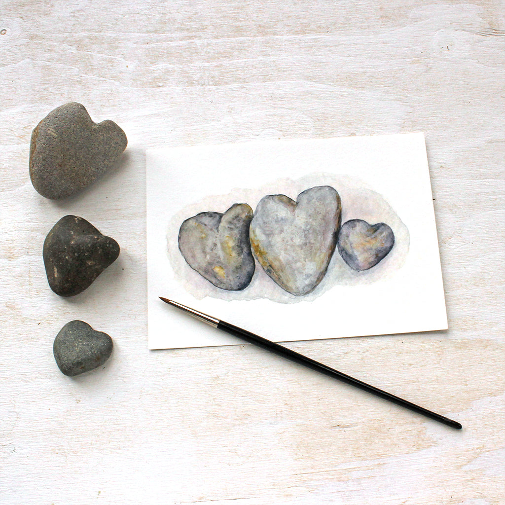 Beautiful watercolor painting of a family of heart-shaped rocks. Artist Kathleen Maunder.