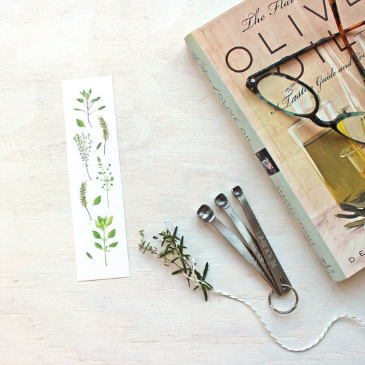 A bookmark featuring herb paintings by watecolor artist Kathleen Maunder. Images include sage, thyme, rosemary, summer savory and basil.