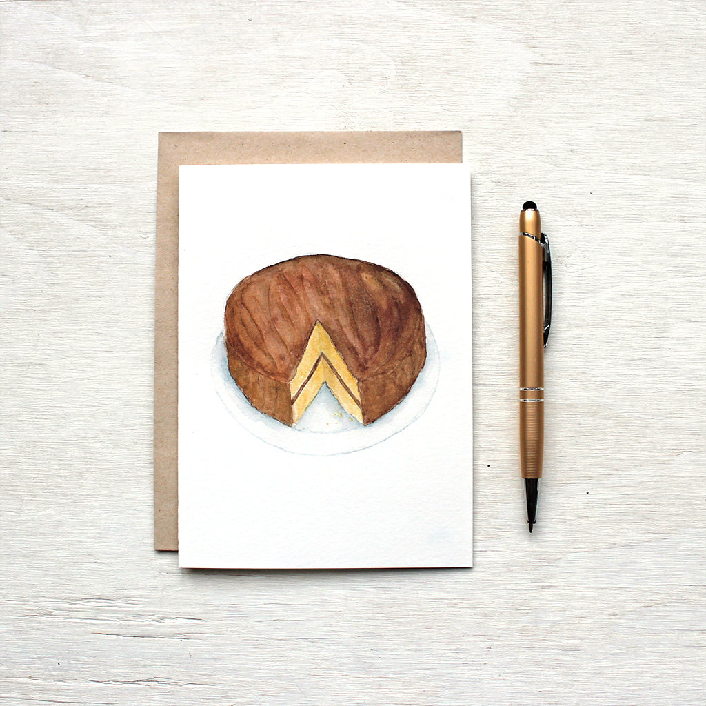 Note card featuring a watercolor painting of a vanilla and chocolate layer cake. Artist Kathleen Maunder.