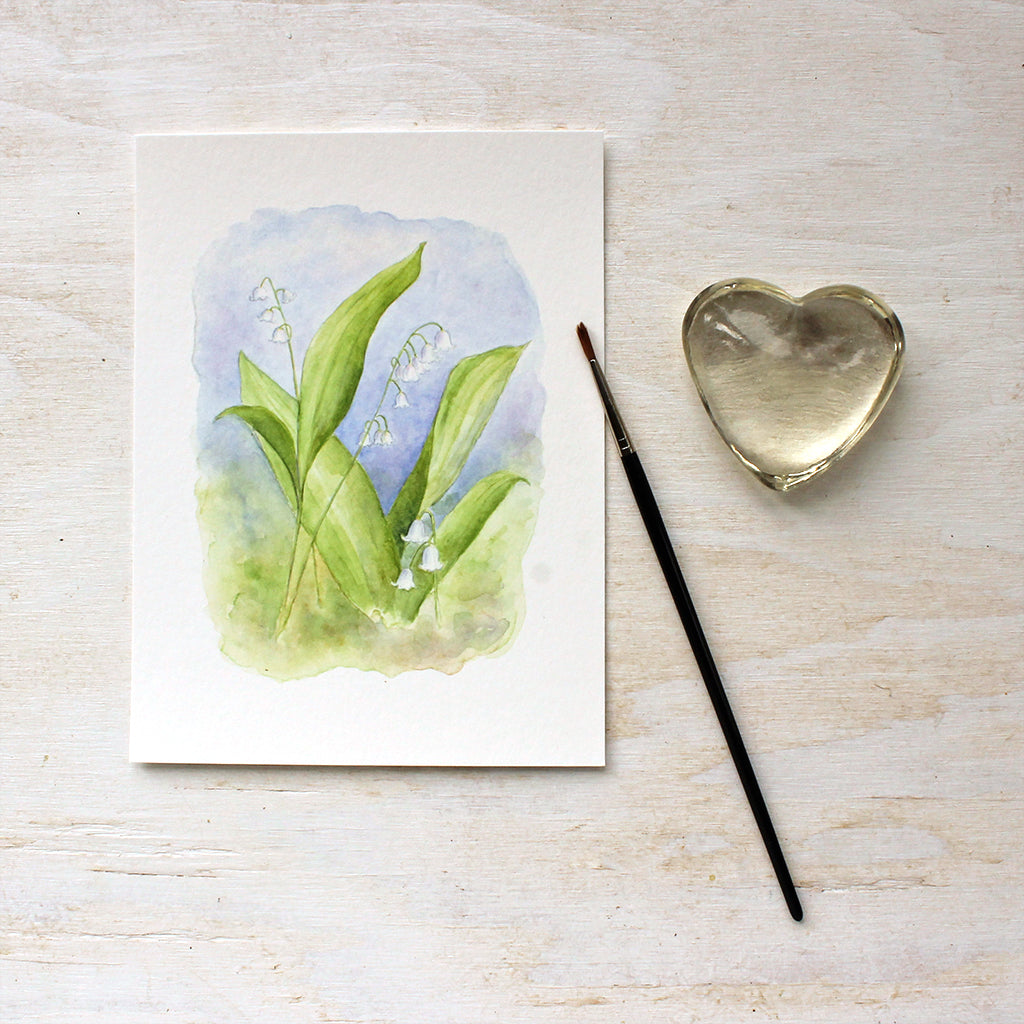 An art print of a delicate watercolour painting of lily of the valley by Kathleen Maunder. Beautiful tones of white, green and blue.