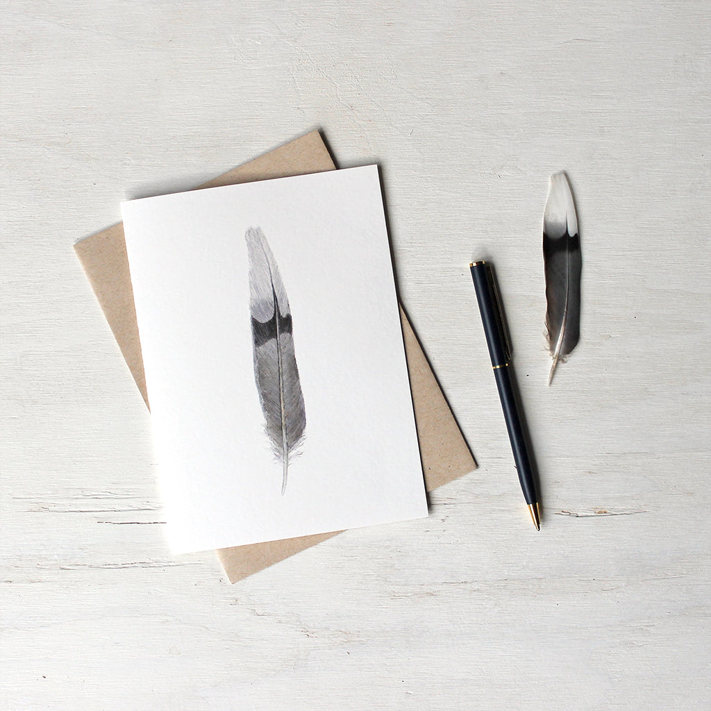 Note card featuring a watercolor painting of a black, gray and white mourning dove feather. Artist Kathleen Maunder.