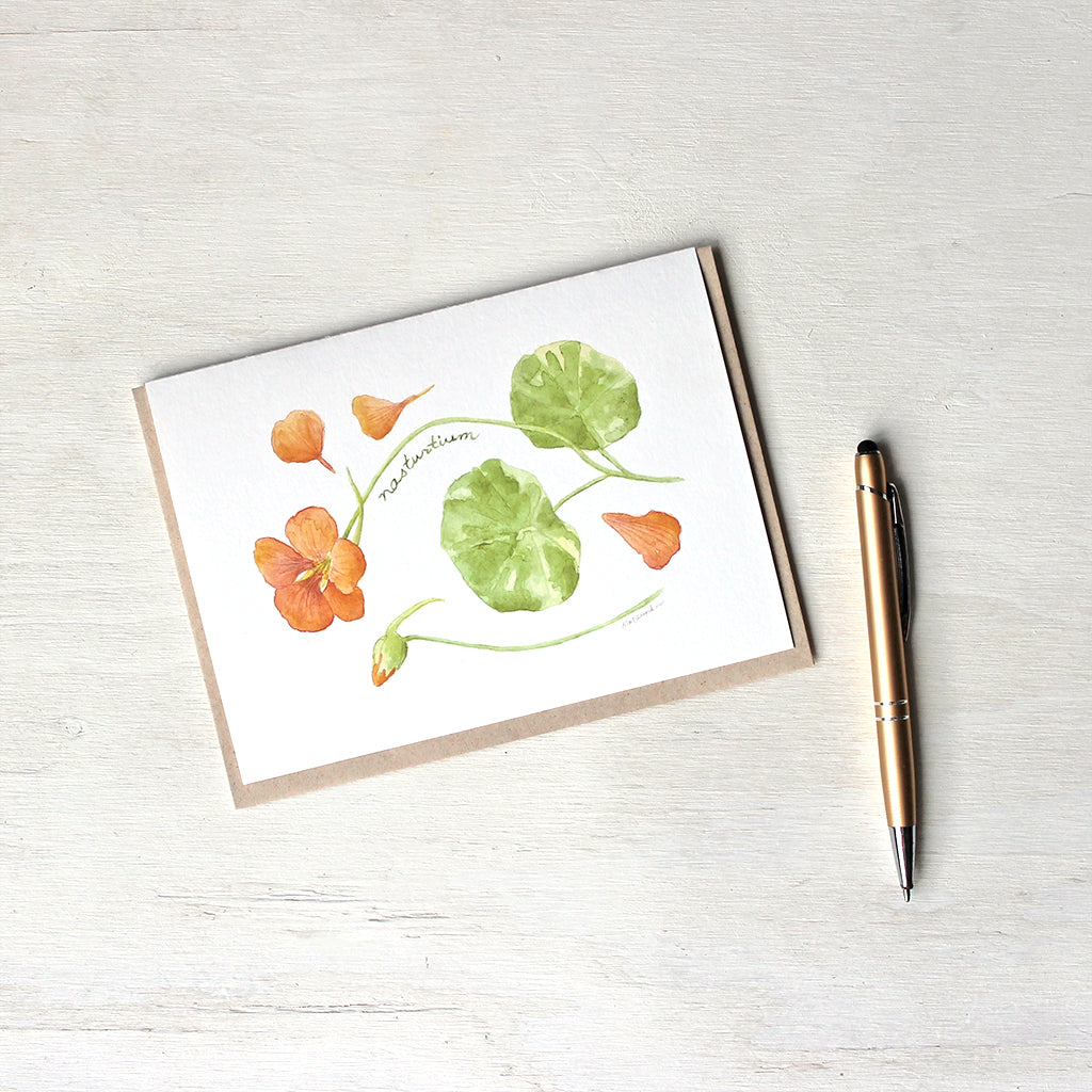 Note card featuring a watercolor painting of an orange nasturtium flower, petals, bud and leaves. Artist Kathleen Maunder.