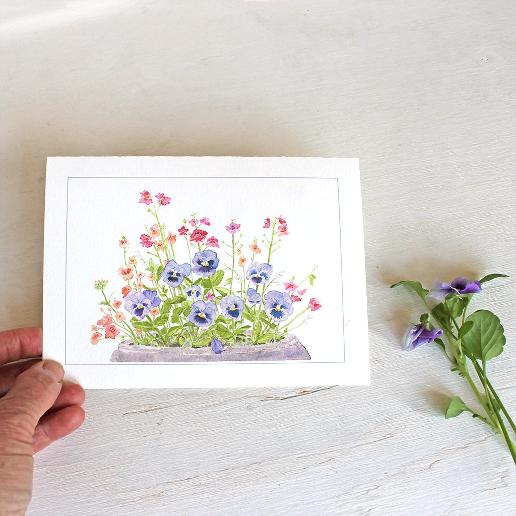 Note card featuring watercolor painting of purple-blue pansies, nemesia, diascia and euphorbia. Artist Kathleen Maunder.