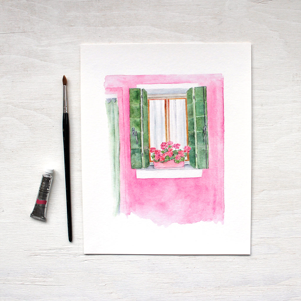 Art print featuring a watercolor of a pink and green house with geraniums in Burano, Italy. Artist Kathleen Maunder.