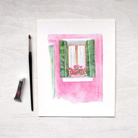 Art print featuring a watercolor of a pink and green house with geraniums in Burano, Italy. Artist Kathleen Maunder.