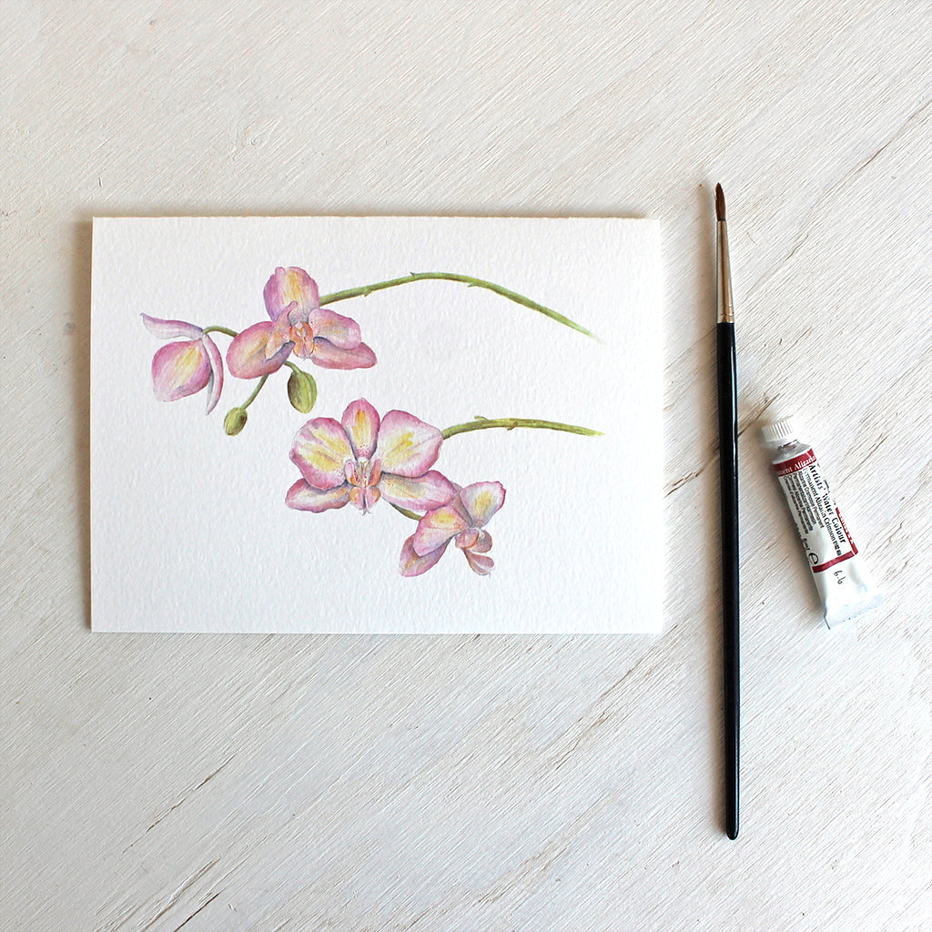 Note card featuring a watercolour painting of pink and yellow orchids. Artist Kathleen Maunder.