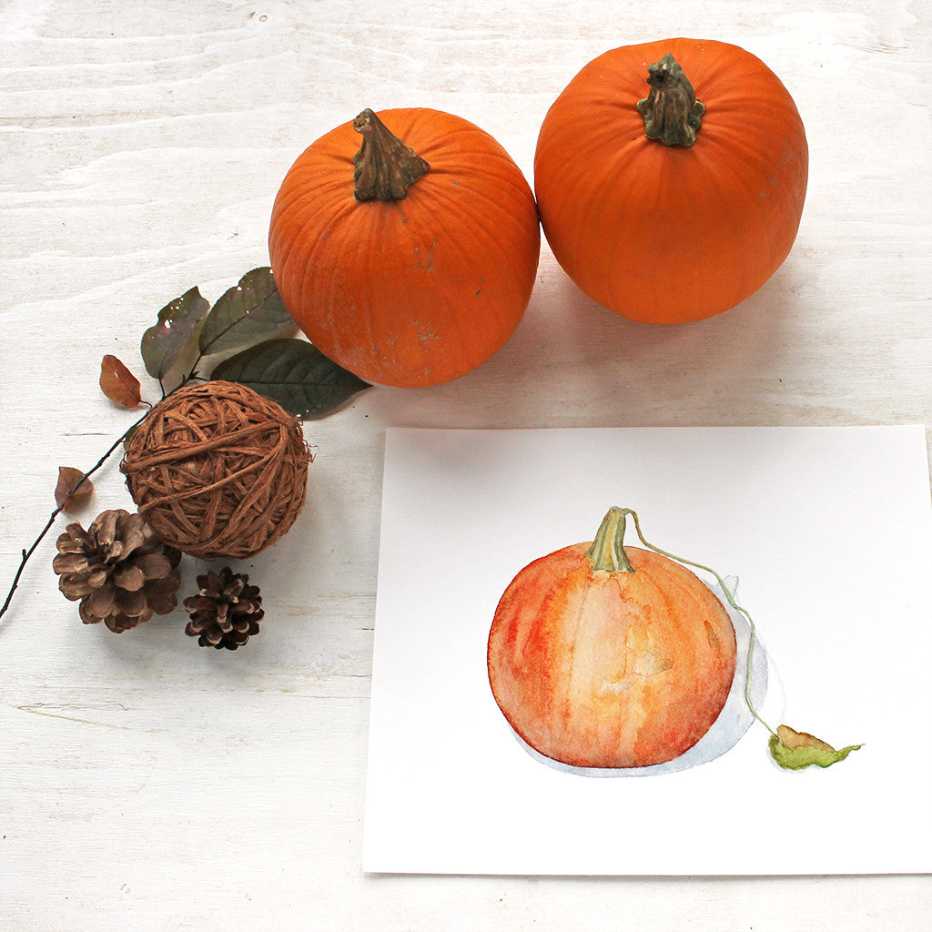 Art print of a watercolor painting of an orange pumpkin with leaf. Artist Kathleen Maunder.