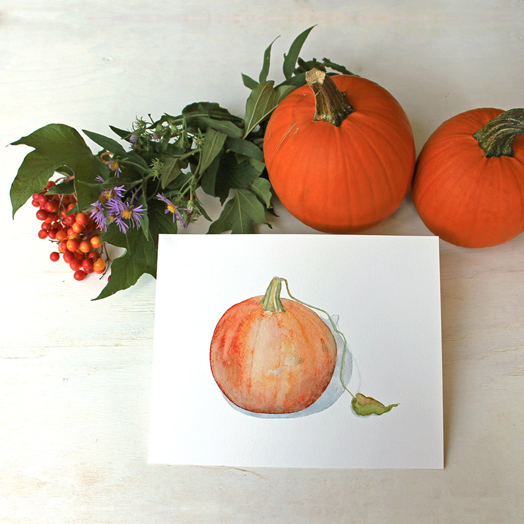 Watercolor art print of a painting of an orange pumpkin with leaf. Artist Kathleen Maunder.