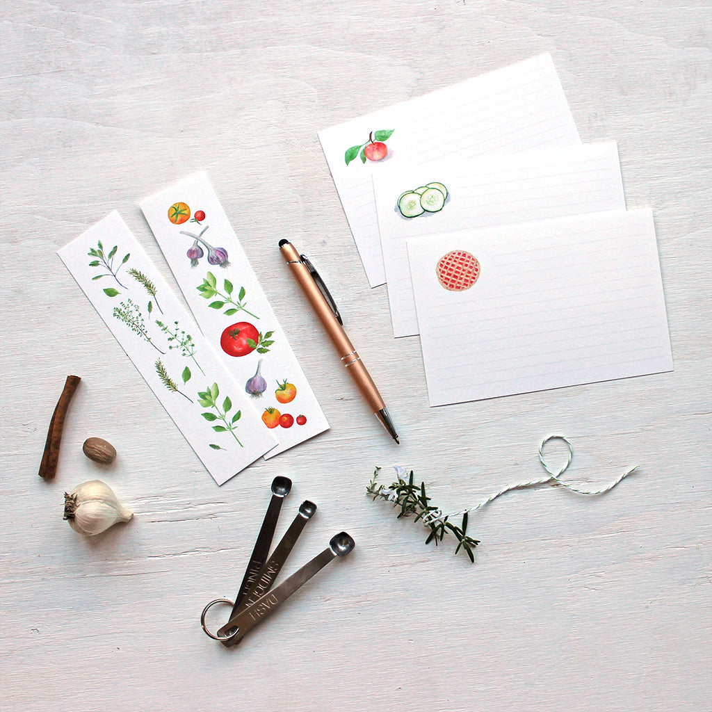 Bookmarks and recipe cards featuring the watercolour paintings of artist Kathleen Maunder. Among the images included are herbs, tomatoes, apples, cucumber and pie.