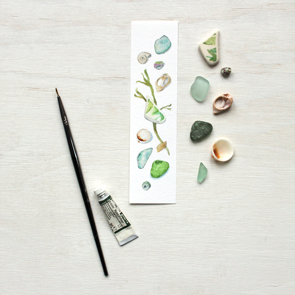 Paper bookmark with watercolor painting of sea finds (seashells, sea weed and beach glass)