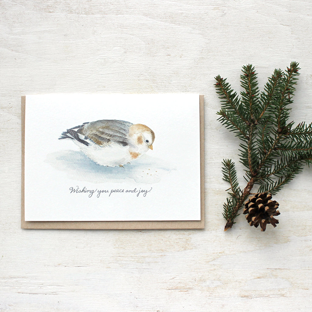 A lovely bird holiday card featuring a watercolor painting of a fluffy snow bunting and the simple, warm greeting: 'Wishing you peace and joy'. 