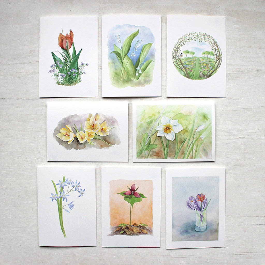 Set of eight spring floral note cards featuring the watercolour artwork of Kathleen Maunder. Images include a tulip and violets, lily of the valley, a secret garden, yellow crocuses, a white daffodil, chionodoxa, a red trillium and a tiny spring bouquet.