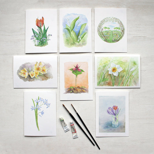 An assortment of eight spring floral note cards featuring the watercolor artwork of Kathleen Maunder. Images include a tulip and violets, lily of the valley, a secret garden, yellow crocuses, a white daffodil, chionodoxa, a red trillium and a tiny spring bouquet.