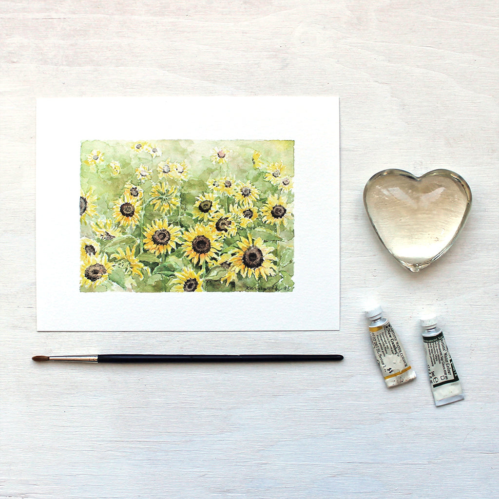 A beautiful art print featuring a watercolor painting of a sunflower field. Lovely golds and greens. Artist Kathleen Maunder.  
