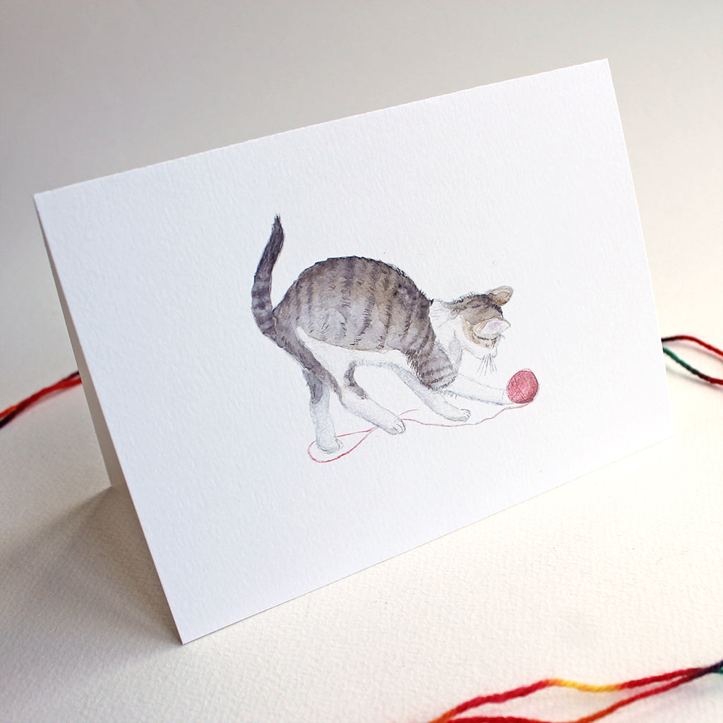 Cat note card featuring a watercolor painting of a tabby kitten playing with a red ball of yarn. Artist Kathleen Maunder.
