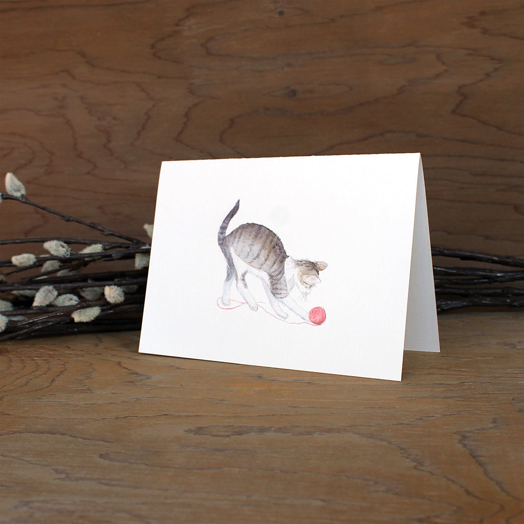 Note card featuring a watercolor painting of a tabby kitten playing with a red ball of yarn. Artist Kathleen Maunder.