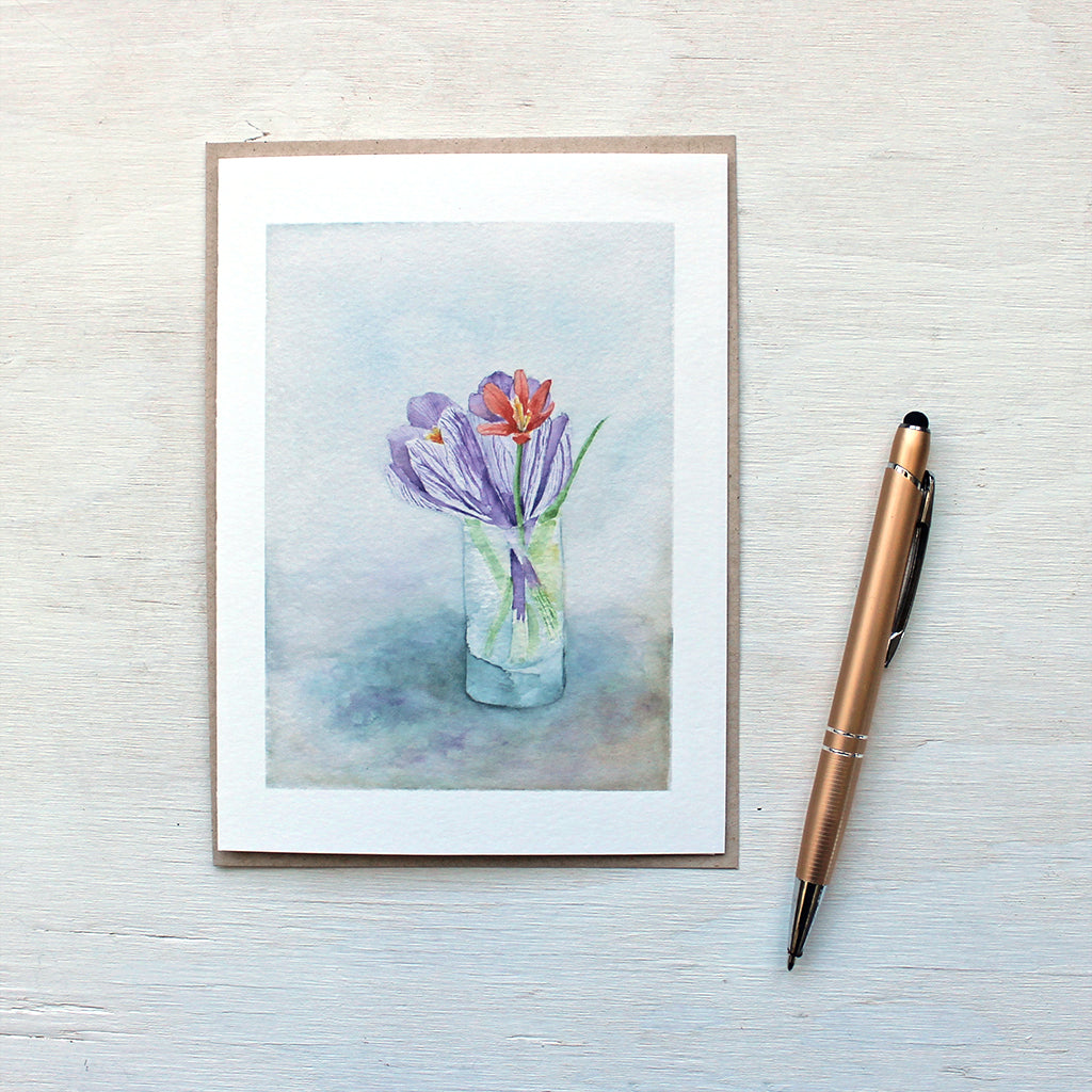 A note card featuring a watercolor painting of a tiny vase of spring flowers: two crocuses and a botanical tulip. Artist Kathleen Maunder.