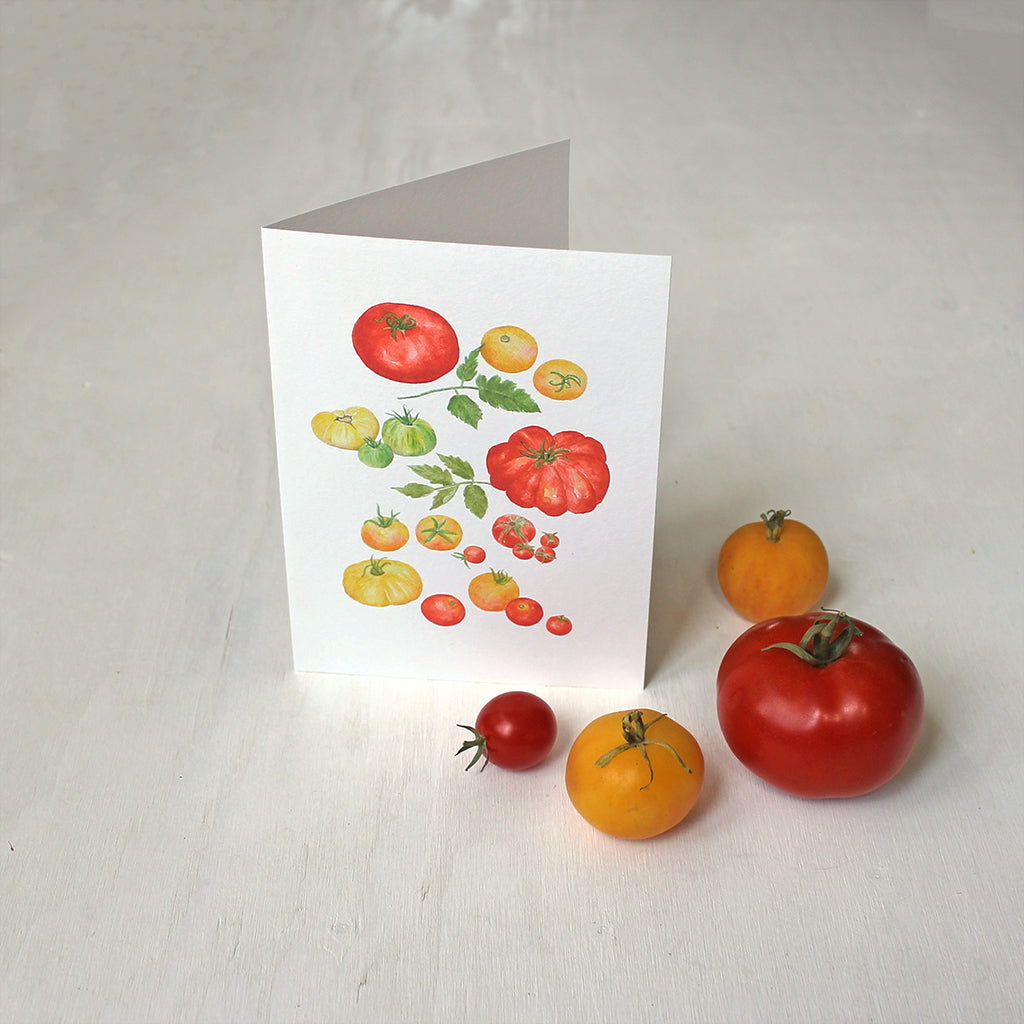 A note card depicting several kinds of red, yellow and green heirloom tomatoes by watercolour artist Kathleen Maunder.