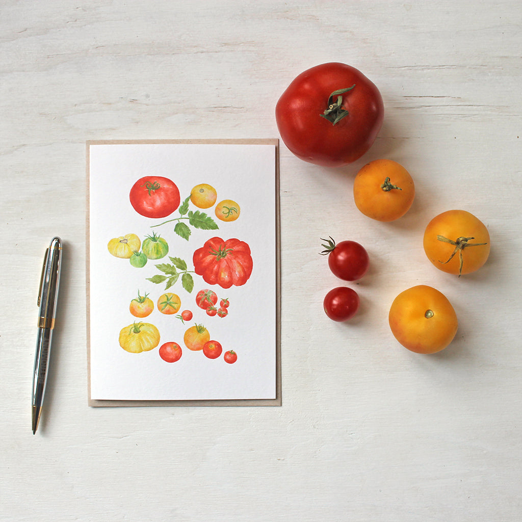 A watercolor note card with paintings of several kinds of red, yellow and green heirloom tomatoes by artist Kathleen Maunder.