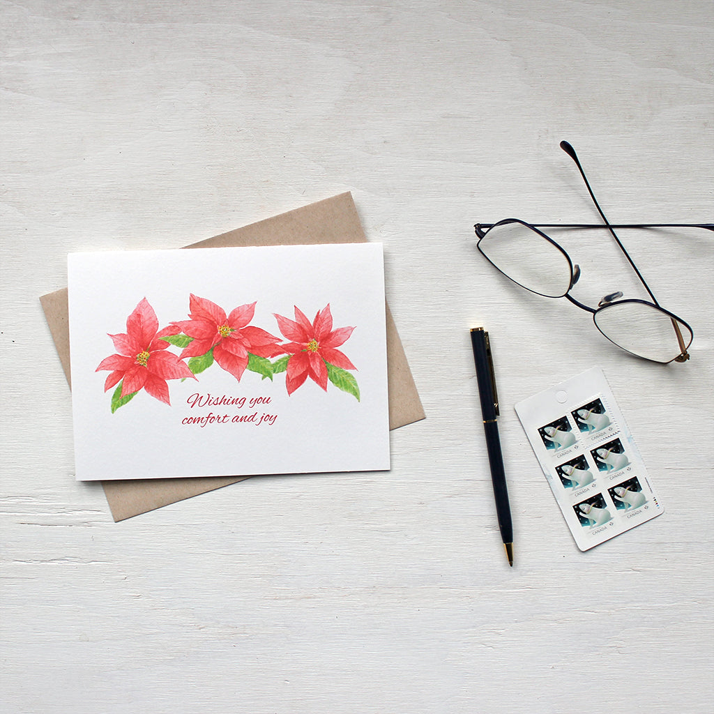 Holiday greeting card featuring three red poinsettia blooms by watercolor artist Kathleen Maunder.