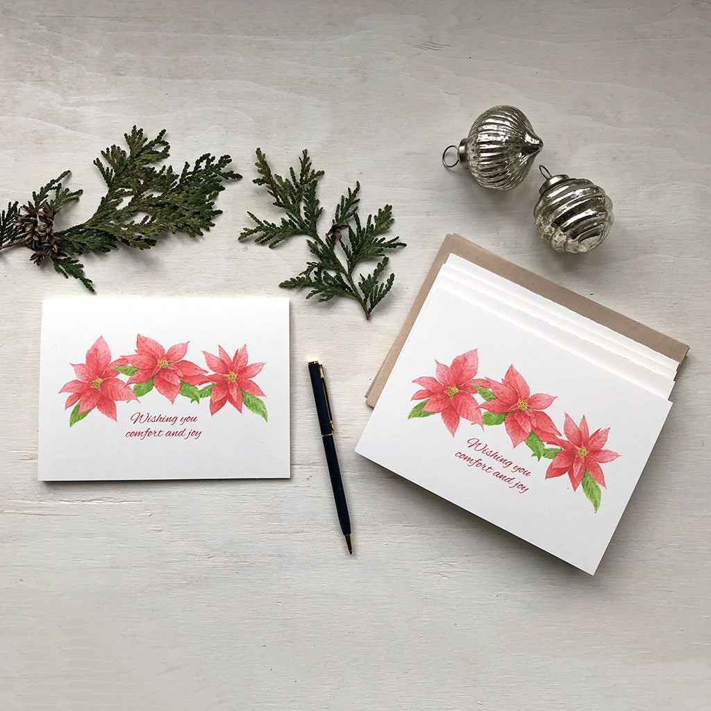 Set of Christmas cards featuring red and green poinsettia blooms painted in watercolor. Artist Kathleen Maunder.