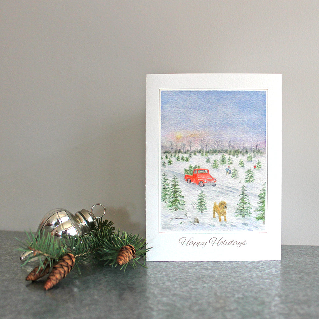 Holiday card featuring a watercolor of a Christmas tree farm with a red truck in the background and a dog in the foreground. Artist Kathleen Maunder