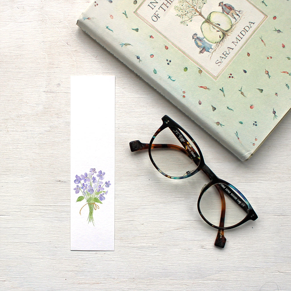 A watercolor painting of a bouquet of violets printed on a paper bookmark.