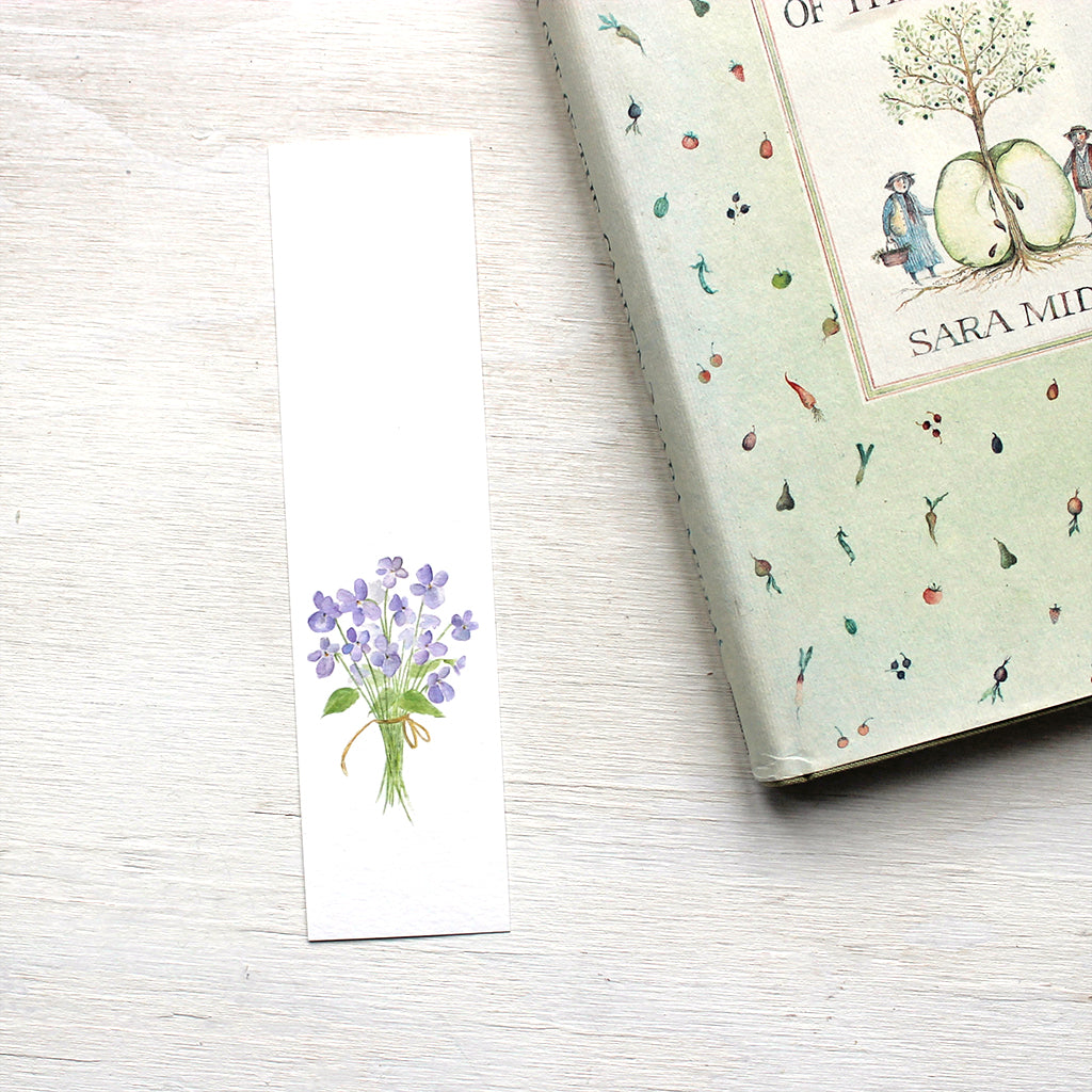 Paper bookmark featuring a watercolor painting of a bouquet of violets. Artist Kathleen Maunder.