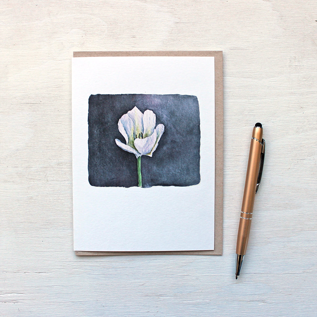 A note card featuring a beautiful watercolor painting of a single white tulip against a dark background. Watercolor artist Kathleen Maunder.