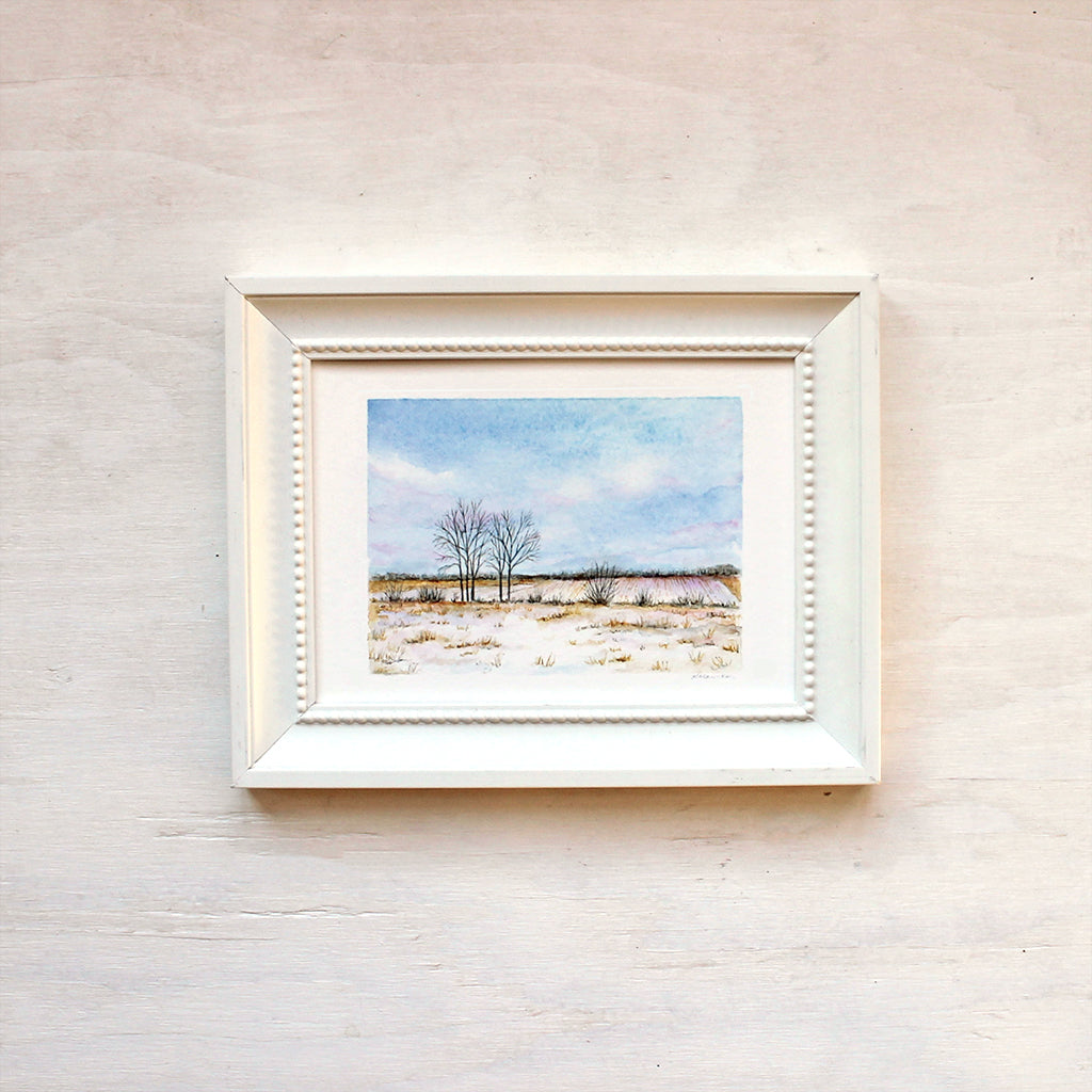 Framed art print featuring a watercolor painting of a winter field and sky. Artist Kathleen Maunder.
