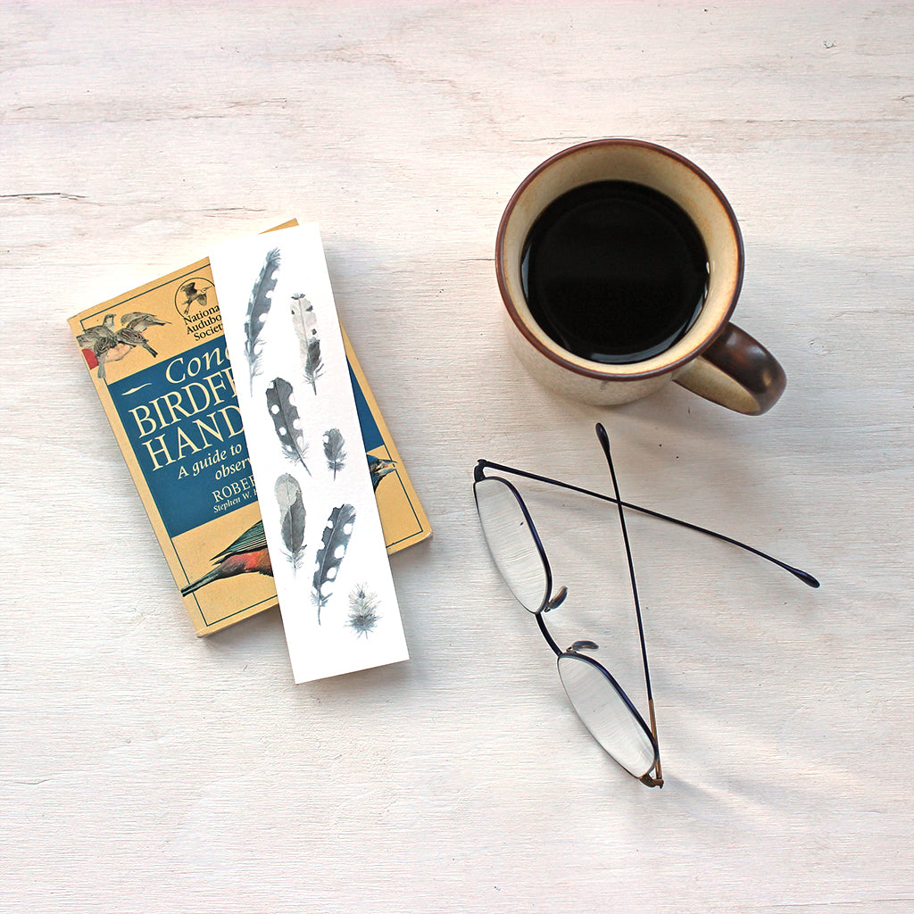 Bookmark featuring a watercolor painting of seven woodpecker feathers by artist Kathleen Maunder 