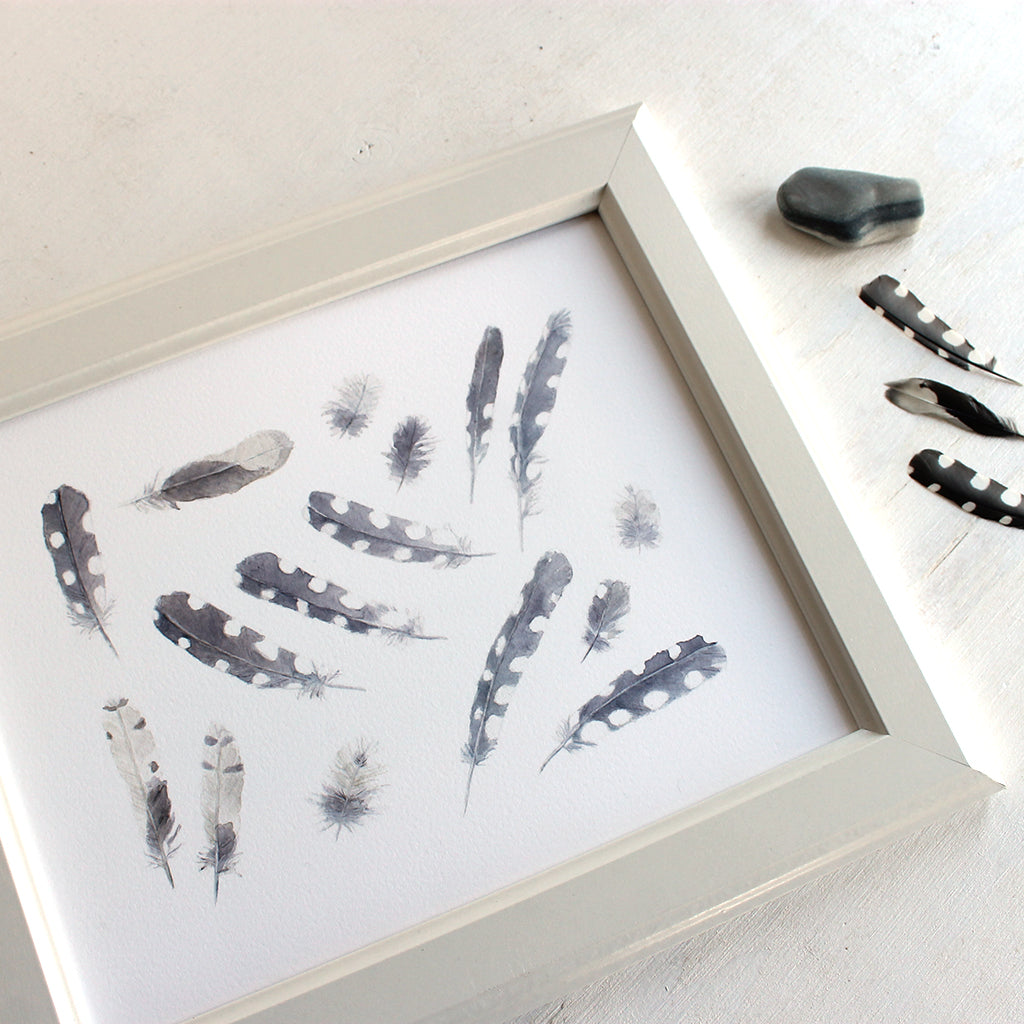An art print featuring a watercolor painting of sixteen woodpecker feathers. Artist Kathleen Maunder.