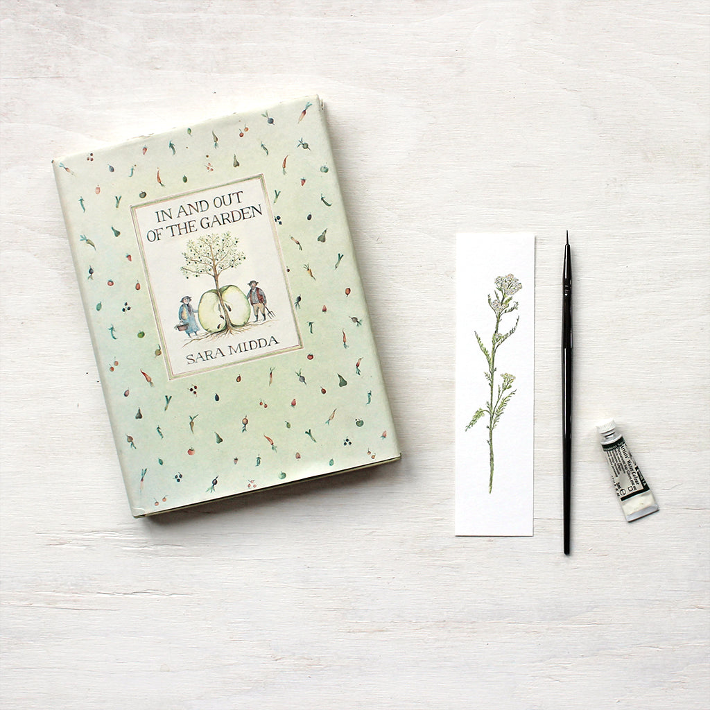 Watercolor bookmark featuring a painting of a stem of white yarrow (Achillea millefolium) by artist Kathleen Maunder
