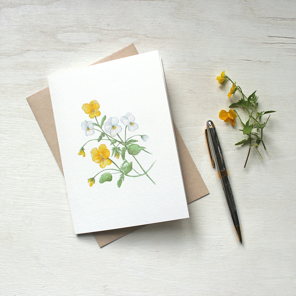 Note card featuring a watercolor painting of yellow and white violas. Artist Kathleen Maunder.